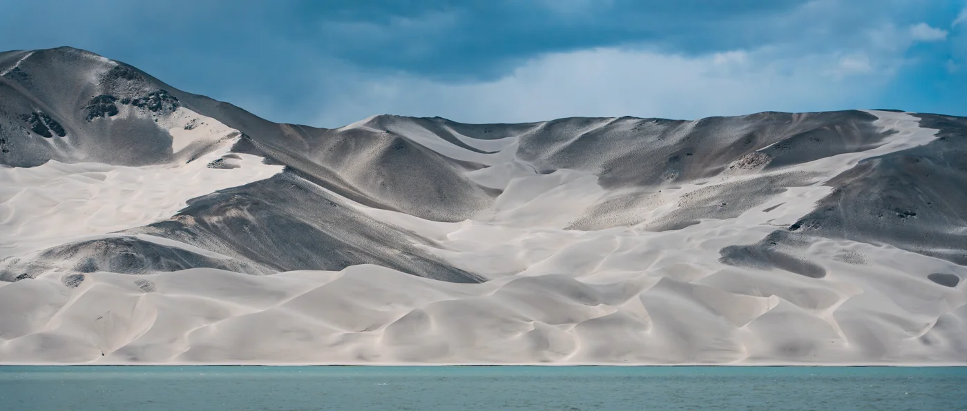 White mountain slopes beside a blue lake